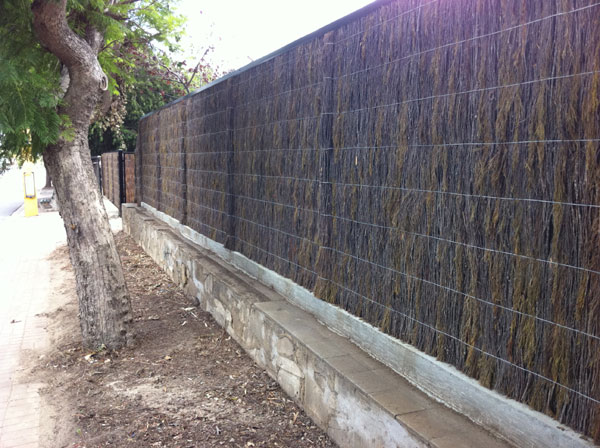 New machine compressed brush panel fence with colorbond capping top finish and brush driveway gates,  set behind existing stone wall.