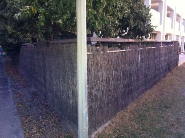 Image:   With this corner fence, the left hand side can be repaired by lifting and patching, but the brushwork on the right hand side section has reached its use-by date will need to be replaced with new machine compressed panels.  The posts and base can be re-used, but the capping should be replaced.  Sometimes it is necessary to sleeve or replace old posts where non-galvanised material was used and they have corroded.